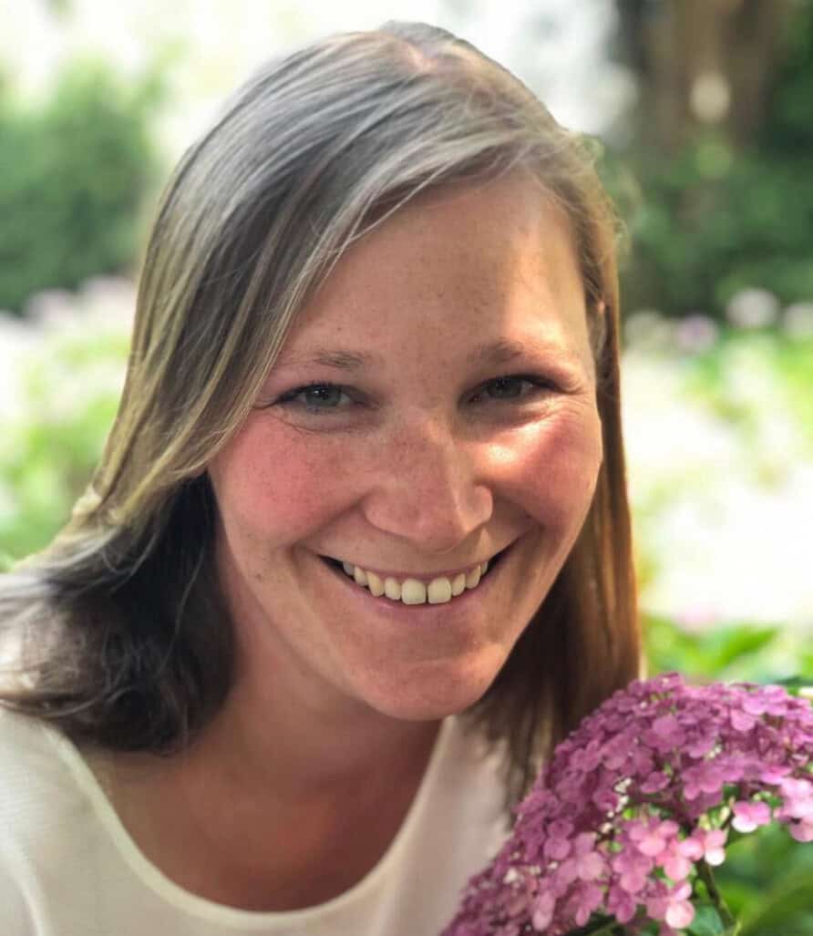 Lächelnde Frau mit violettem Hydrangea im Garten, Natur, Glücksmoment, Gartenarbeit, schöne Blumenbilder.